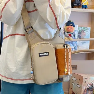 Detail view of a khaki and orange crossbody sports bag with a bottle holder for hiking
