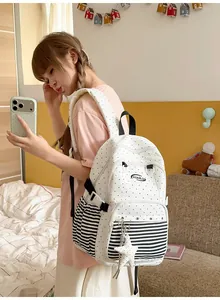 Student in pink outfit wearing a white polka dot and striped backpack with star charm