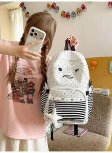 Detailed view of a preppy white polka dot backpack featuring a cute star keychain accessory