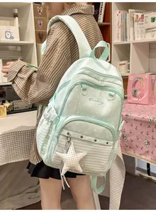 Detail shot of a light green student backpack with star patterns and a star charm.