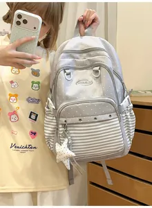 Grey preppy school backpack with polka dots and stripes worn by a student model