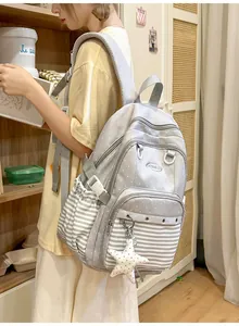Detail view of the stylish grey polka dot backpack worn by a student in a cozy room