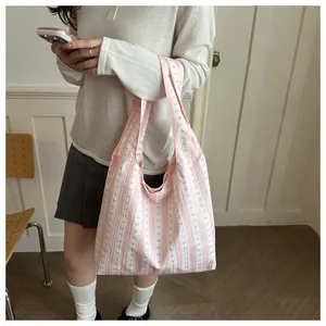 Pink and white striped tote bag with bow pattern carried by a model in lifestyle shot.