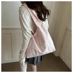 Detailed view of pink striped tote bag with bow pattern worn by an Asian model