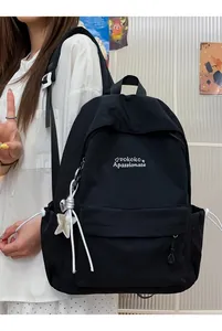Zaino per studenti nero minimalista con ciondolo a stella in un ambiente di campus