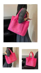 Detail of a bright pink nylon tote bag featuring multi-pocket design and macro textures.