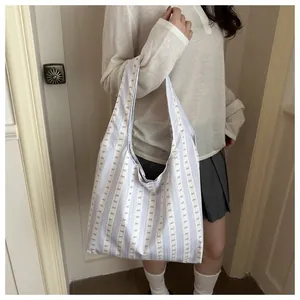 Detailed view of a light blue striped tote bag with bow patterns on a model's shoulder.
