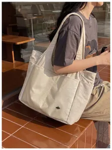 Detailed view of the large cream nylon tote bag featuring a multi-pocket design