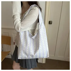 Detailed shot of a light purple striped hobo bag with small bow patterns and shoulder strap.