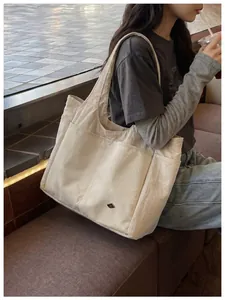 Detailed side view of a large beige nylon travel shoulder bag in a cafe setting
