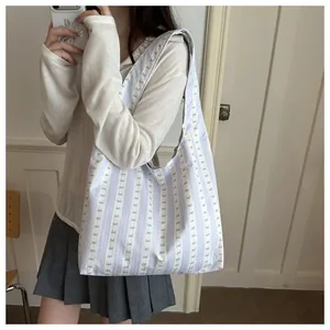 Lifestyle view of a blue and white striped shoulder bag showing fit and aesthetic.