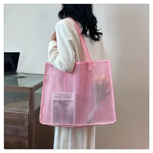 Vista detallada de un bolso de malla rosa grande llevado por una modelo con estilo.