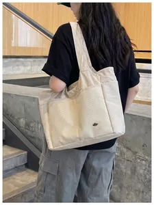 Close-up detail of a beige large capacity nylon tote bag with multiple pockets worn by a model