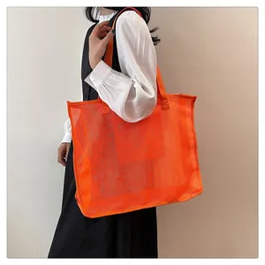 Gran bolso de malla naranja llevado por una modelo para un estilo playero y elegante