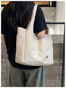 Detailed view of a large beige nylon tote bag with multiple pockets shown on a model's back