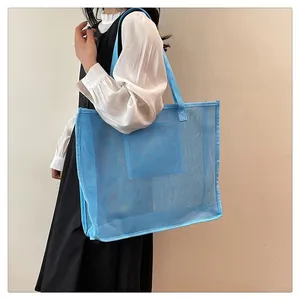 Detalle de un gran bolso de malla azul llevado por una modelo para la playa y el yoga.