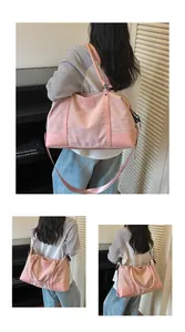 Detailed view of pink embroidered travel bag with adjustable strap and top handles
