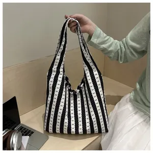Detailed view of striped underarm tote bag held against lifestyle commute backdrop