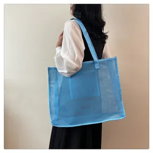 Vista de una modelo con una bolsa grande de malla de nailon azul para la playa o el gimnasio