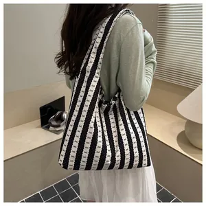 Detail of black and white striped canvas tote bag worn on shoulder for daily commute