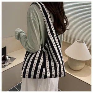 Lifestyle detail view of a striped tote bag with bow patterns worn over the shoulder