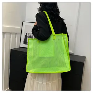 Modelo con un gran bolso de malla verde neón en un entorno interior de estilo moderno.