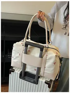 Lightweight white embroidered travel bag with trolley sleeve attached to suitcase handle