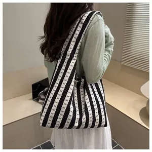 Female model wearing a striped underarm tote bag with cute bow patterns in a cozy room