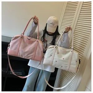 Model holding pink and cream large capacity travel bags with elegant floral embroidery