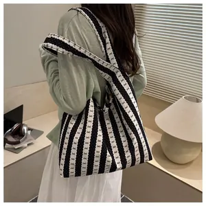 Detailed view of woman carrying a black and white striped tote bag with bow pattern details