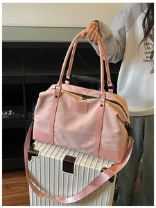 Detailed view of the pink expandable travel bag with embroidered bow patterns on suitcase