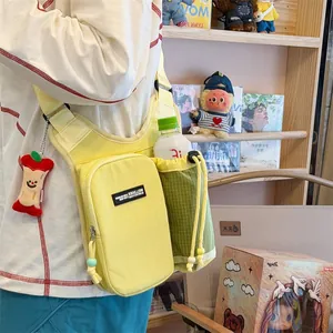 Detail view of yellow crossbody hiking bag with green mesh bottle holder and apple charm