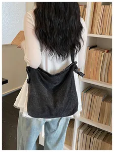 Back view of a vintage black denim messenger bag on a woman in a library setting