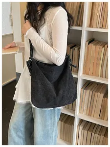 Vintage black denim messenger bag for women worn by a model in a library setting