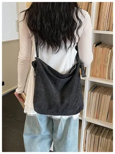 Vintage black denim crossbody bag for women shown in a lifestyle back-view shot with bookshelf.