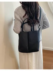 Back view of a minimalist black commuter tote bag with double handles and strap.