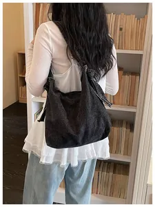 Retro black denim student messenger bag shown in a library with a model back view
