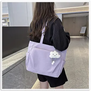 Detailed view of a purple large capacity canvas tote bag with a cute white cloud keychain