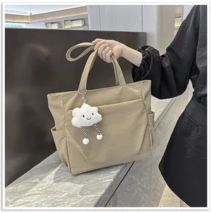 Large capacity khaki nylon tote bag with cute cloud charm being held by a model