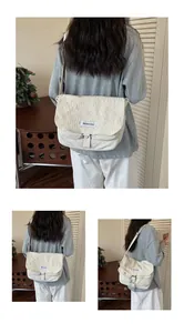 Viste dettagliate di una grande borsa a tracolla in tela testurizzata color crema