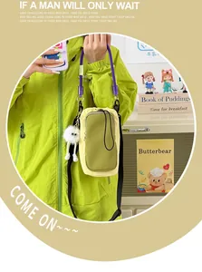 Detail of a bright dopamine style mini crossbody phone bag worn with a green jacket