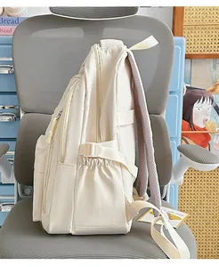 Detailed side view of a cream minimalist water-resistant student backpack on a chair
