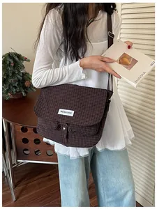 Borsa a tracolla vintage in tela a scacchi marrone su modella con rivista