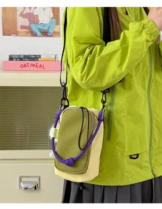 Close-up of a vibrant olive green and beige crossbody phone bag with a purple rope detail