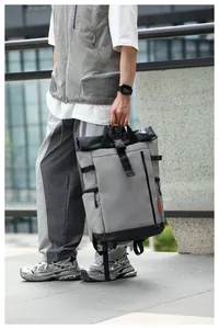 Durable grey waterproof Oxford roll-top backpack held by model in urban street setting