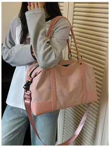 Pink expandable travel bag with butterfly embroidery carried by a woman outdoors