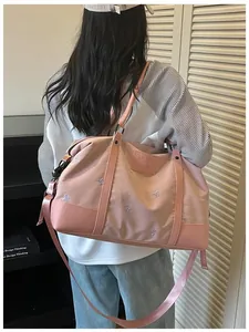 Detail of large pink travel bag for women with embroidery and adjustable shoulder strap