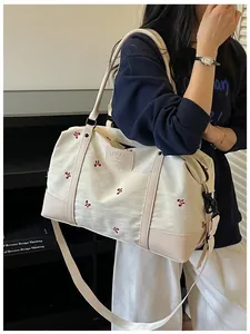 Close-up detail of lightweight cream travel bag with red bow embroidery for women