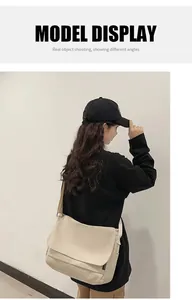 Back view of a large beige canvas messenger bag worn by a model in a trendy casual style