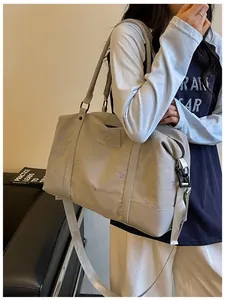 Large stylish beige travel duffel bag with butterfly embroidery carried by a female model